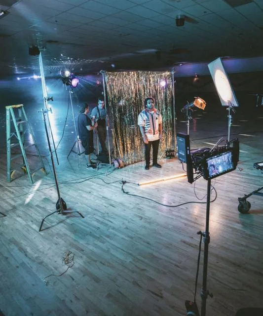 The studio floor lit for a shoot, with lamps, stands and a camera on sticks